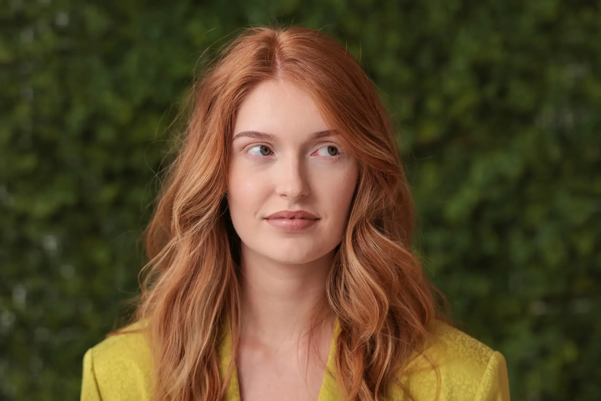 Editorial portret van een roodharige vrouw in groen, gefotografeerd voor een groene wand.